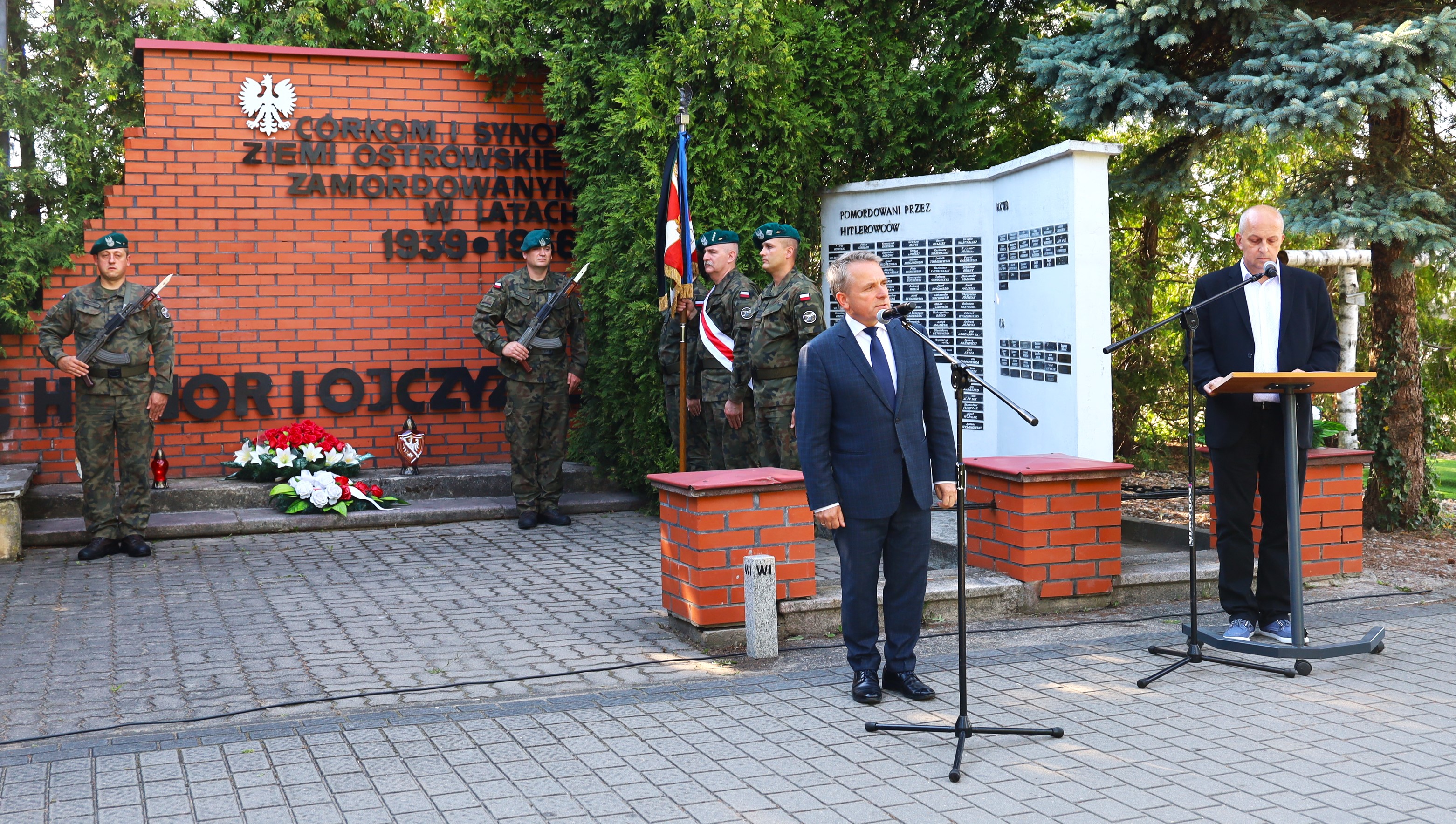 Burmistrz Miasta Jerzy Bauer przemawia podczas uroczystości 1 sierpnia przy przy Mauzoleum „Córek i Synów Ziemi Ostrowskiej zamordowanych w latach 1939 – 1956”, warta z dwóch żołnierzy przy pomniku, oraz delegacja wojskowa ze sztandarem i prowadzący uroczystość Pan Komorowski 