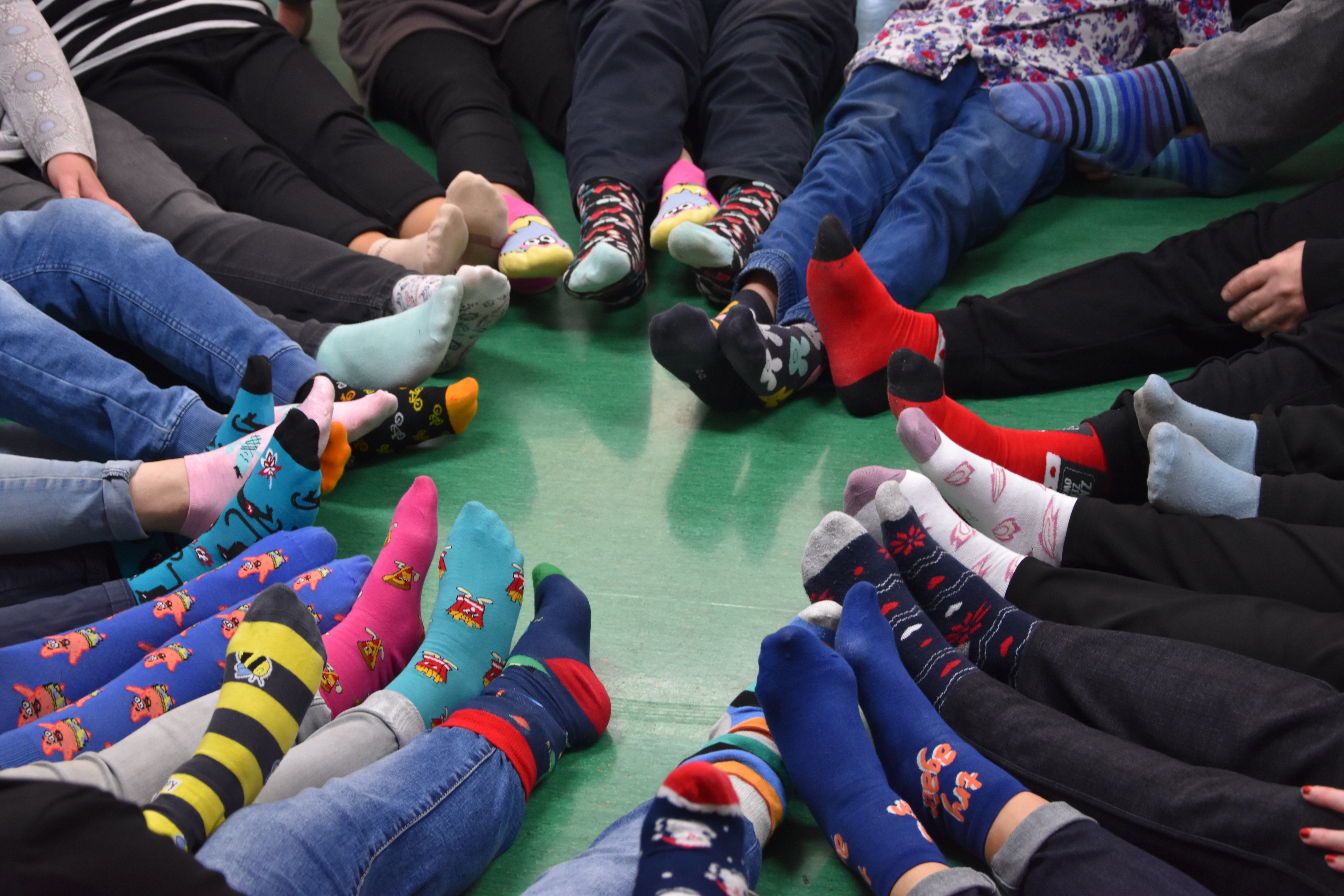 Zdjęcie przedstawia stopy w różnokolorowych skarpetkach na Światowy Dzień Zespołu Downa