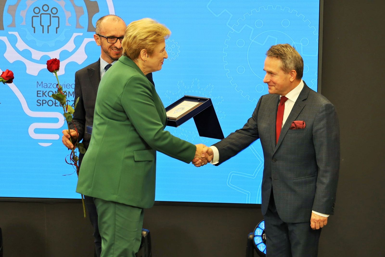 kobieta wręcza mężczyźnie nagrodę