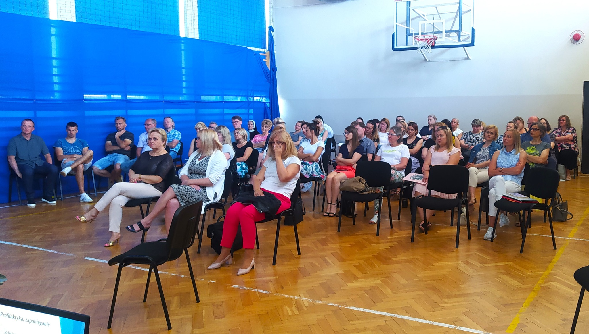 Nauczyciele szkół siedza na hali sportowej w szkole podstawowej podczas spotkania dotyczącego Profilaktyka uzależnień
