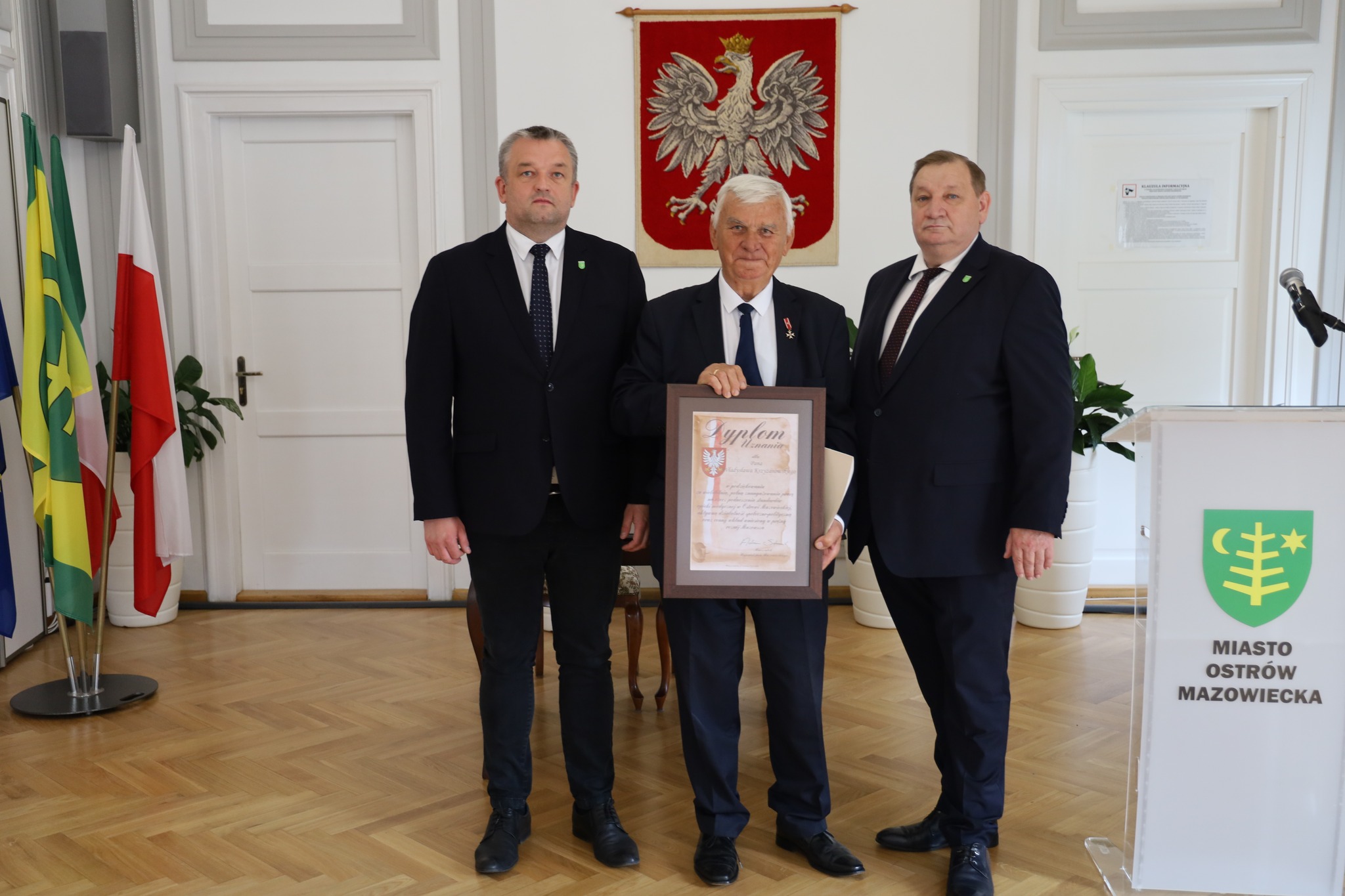 trzy osoby stoją jedna pokazuję swój dyplom