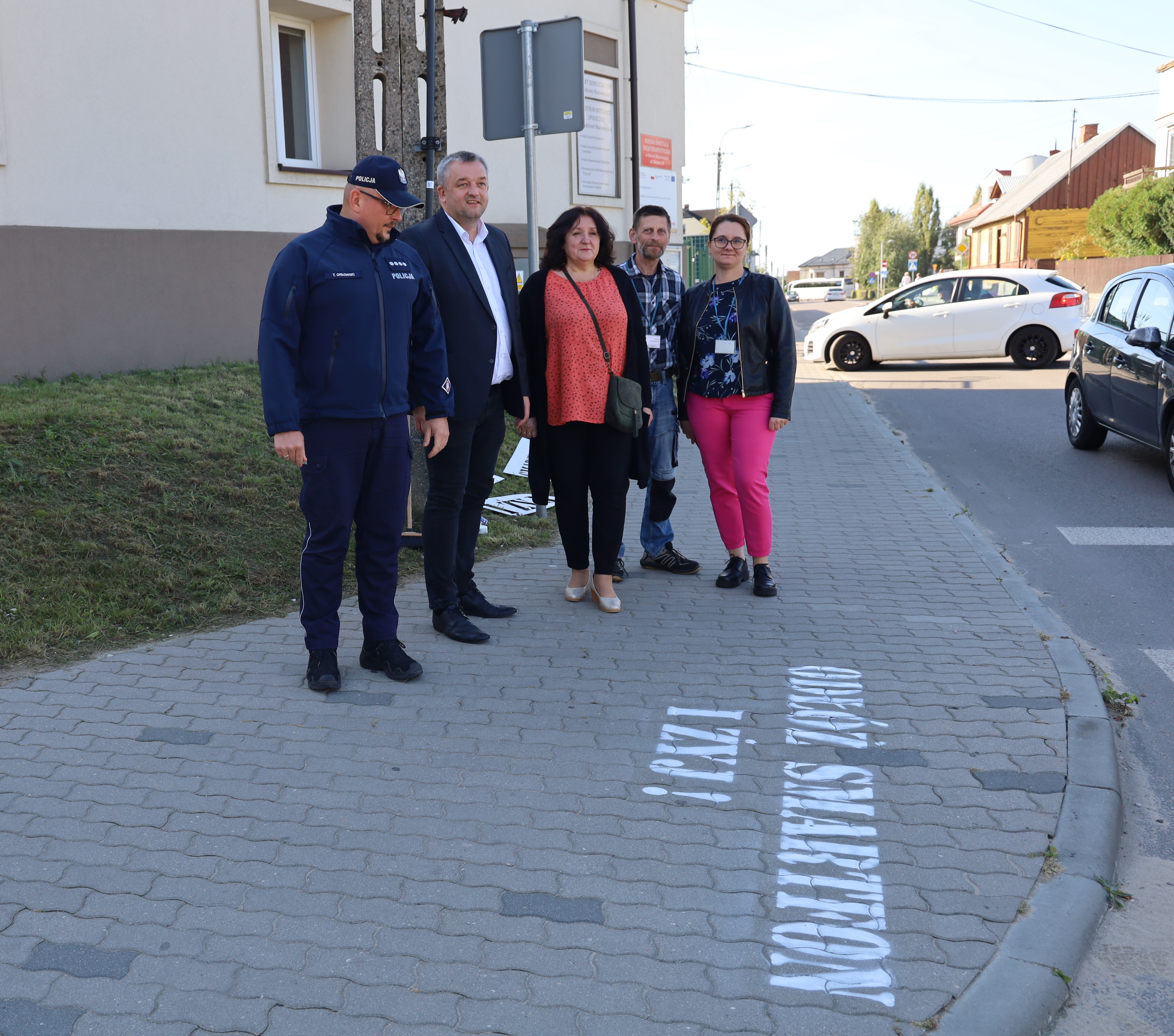 kobiety i mężczyźni przy przejściu dla pieszych którzy wspólnie namalowali napis
