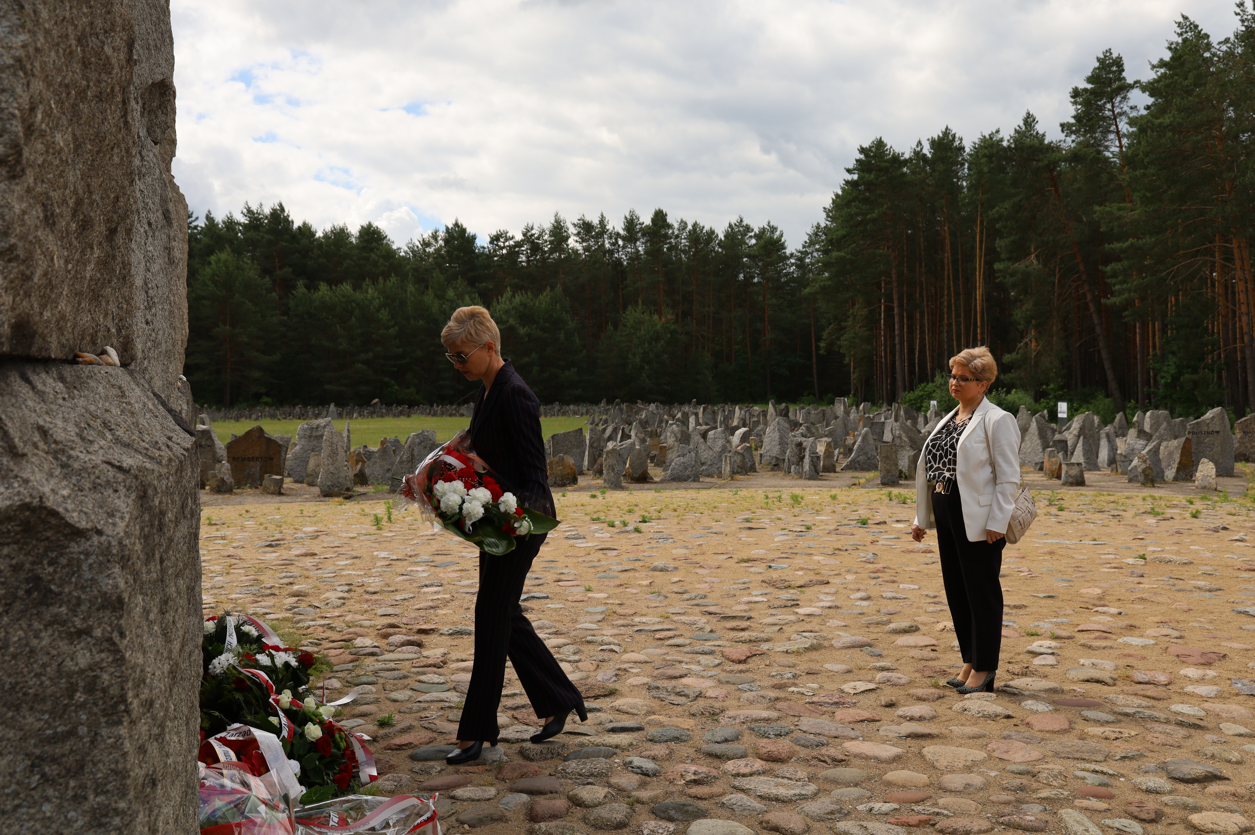 Pod pomnikiem w Muzeum Treblinka w czasie uroczystości składają kwiaty Dyrektor Dorota Ambroziak i Wioletta Ogonowska jako reprezentacja Urzędu Miasta Ostrów Mazowiecka 