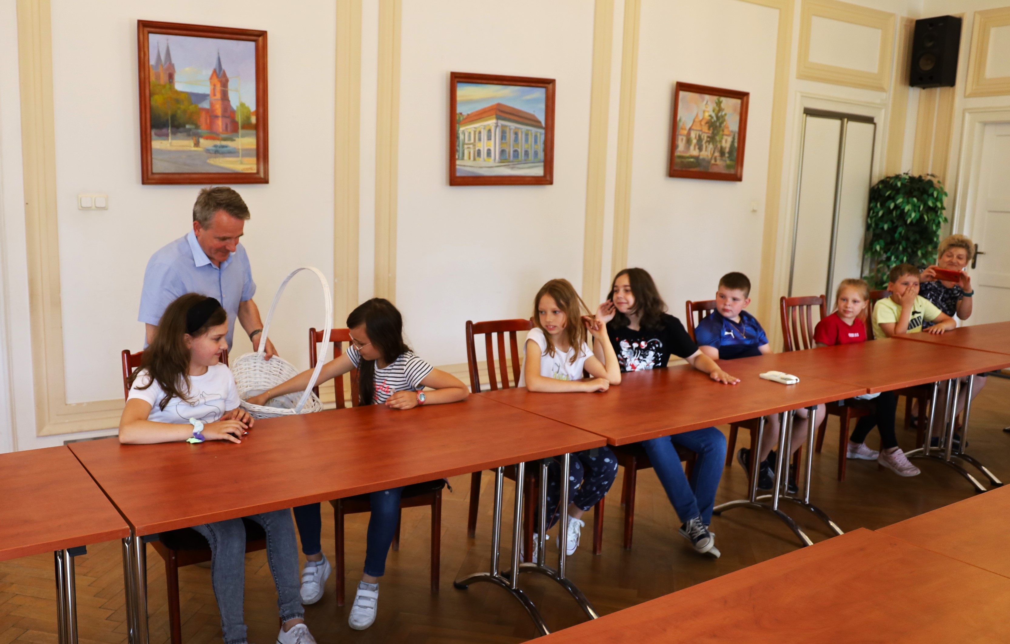 Uczniowie szkoły podstawowej numer 2  zwiedzają ratusz Miejski siedzą na sali konferencyjne a burmistrz miasta Jerzy Bauer rozdaje upominki 