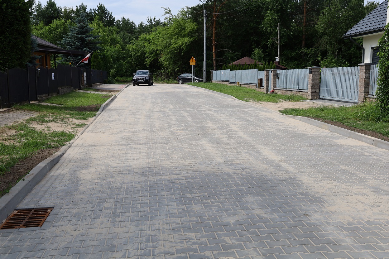 Widok ulicy z kostki brukowej. W oddali samochód.
