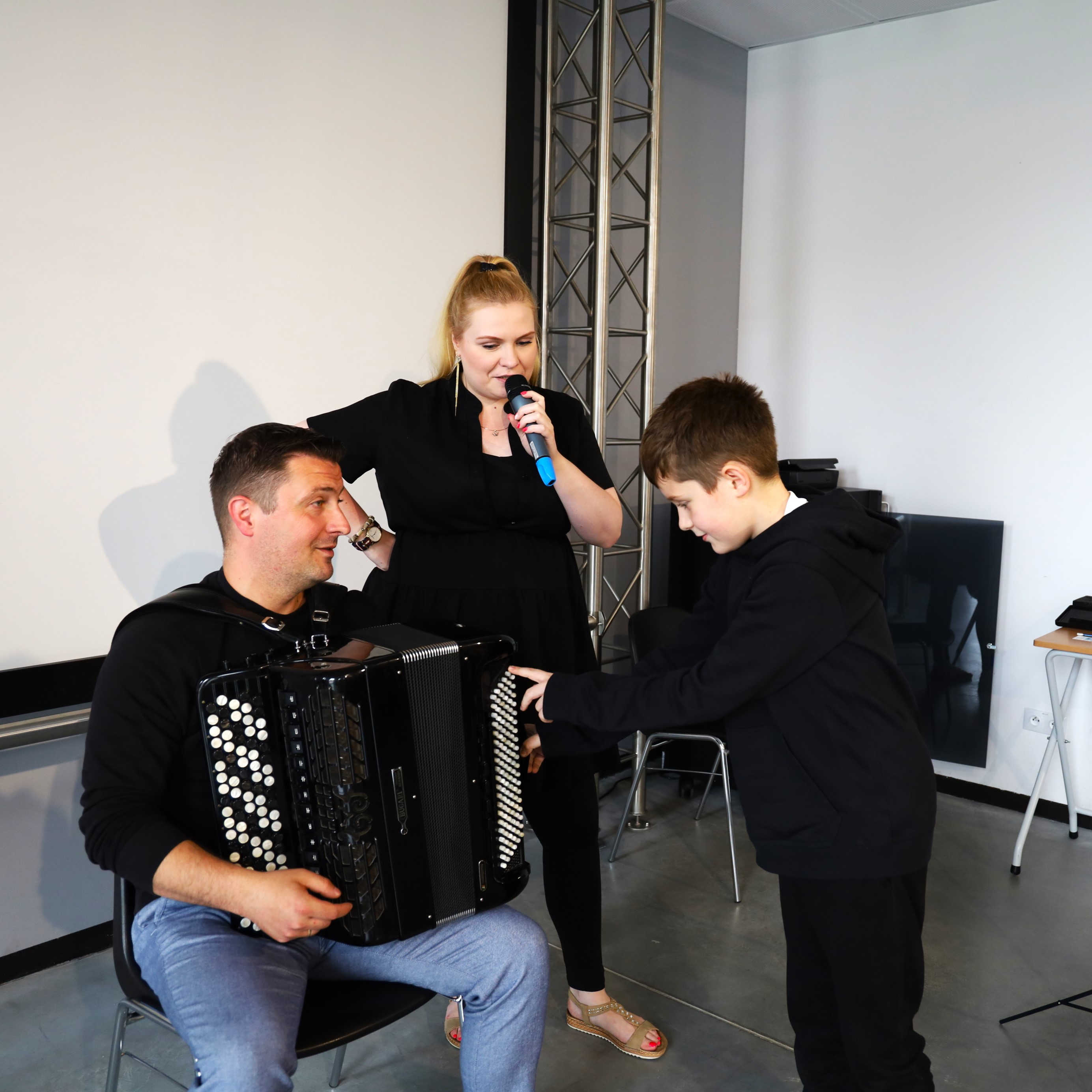 Na zdjęciu chłopiec dotyka akordeonu pana muzyka , prowadząca opowiada przez mikrofon o instrumencie podczas audycji muzycznych w budynku Starej Elektrowni 