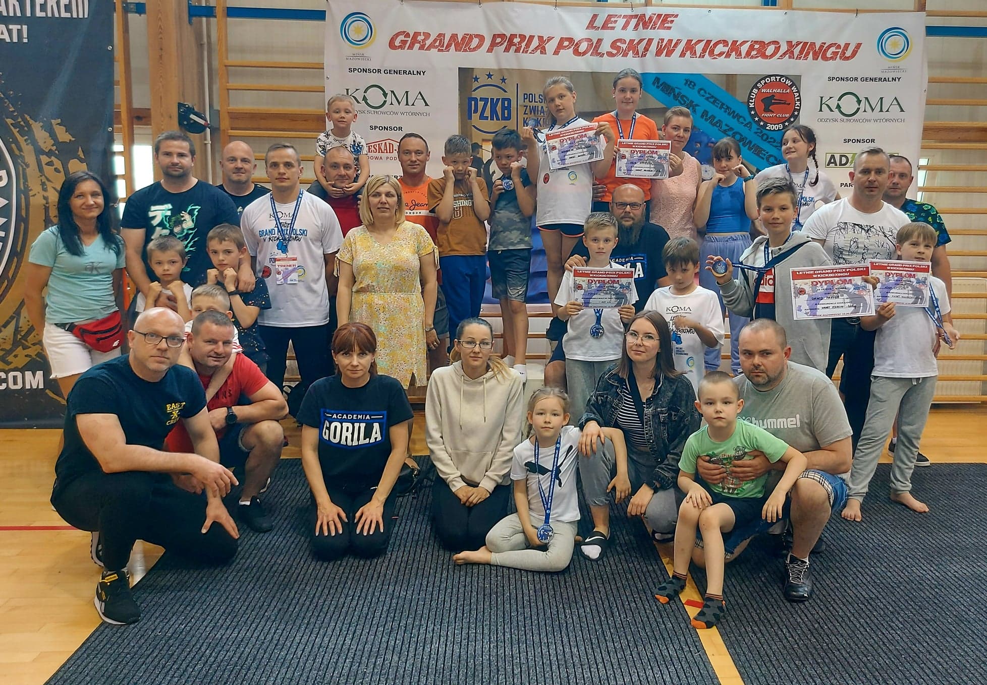 grupa rodziców ,trenerów i dzieci zawodników na wspólnym grupowym zdjęciu podczas letniego grand prix polski w kickboxingu