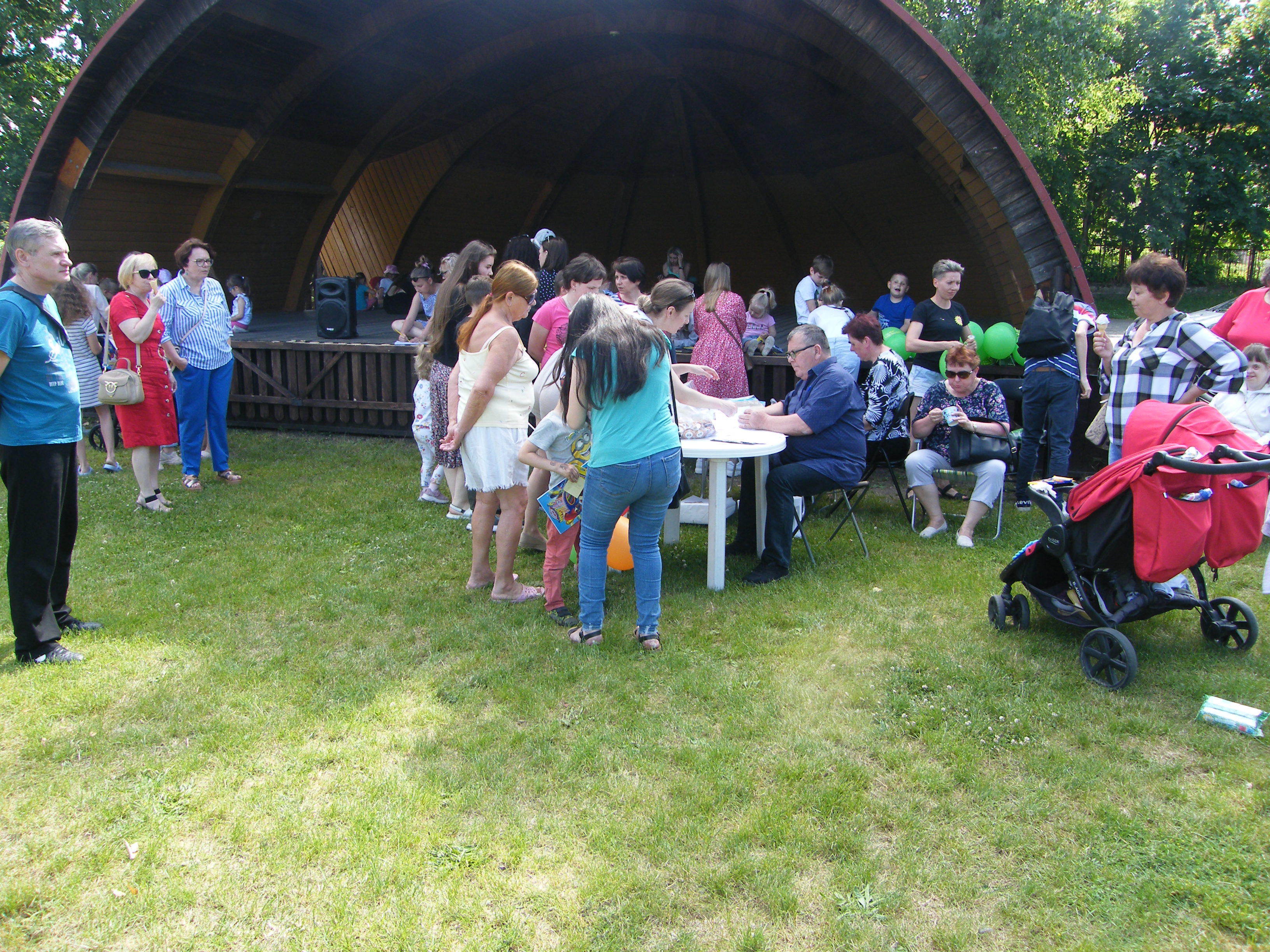 grupa ludzi uczestniczą w pikniku wędkarskim z okazji dnia dziecka. 