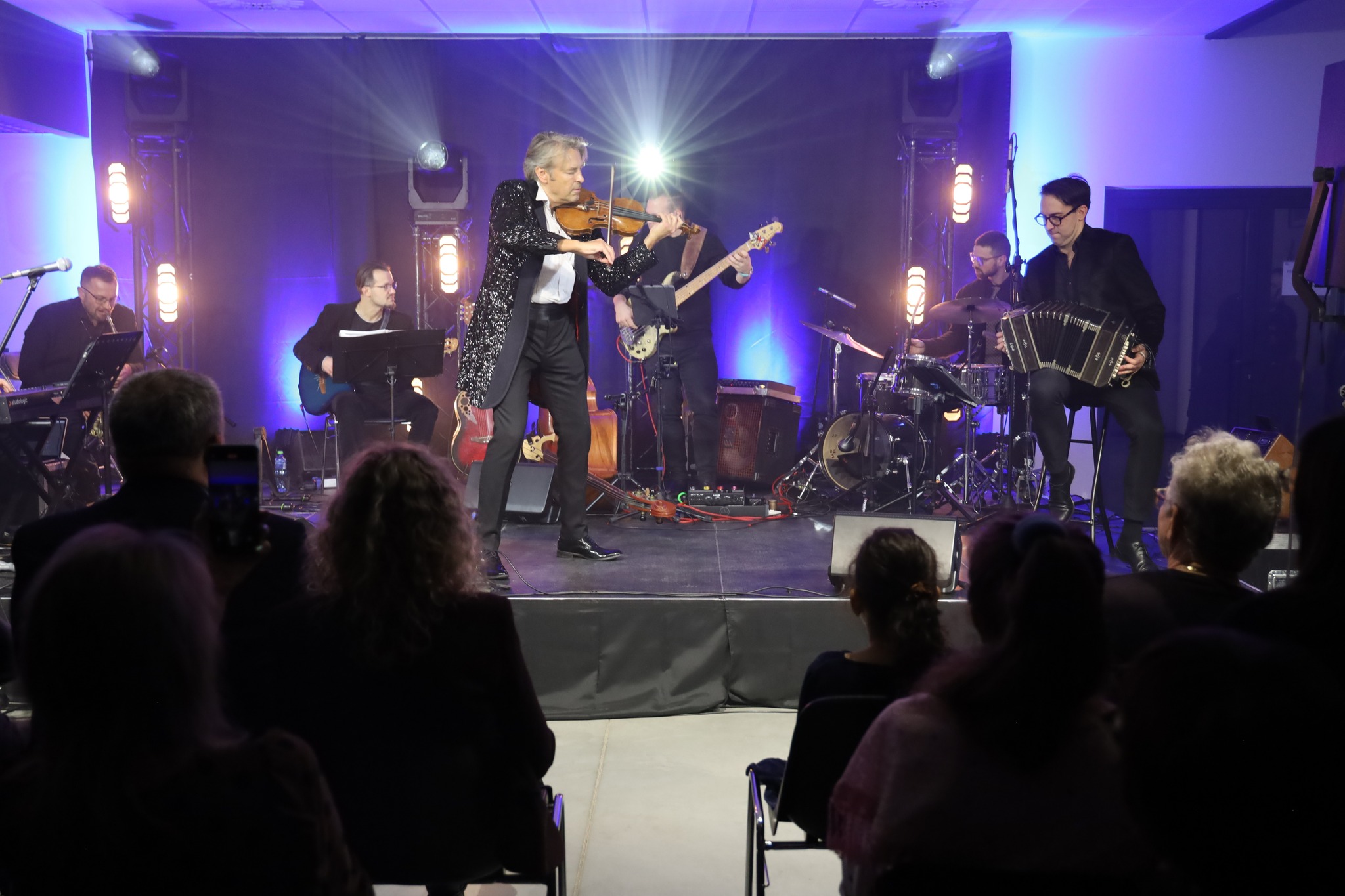 Mężczyzna grający na skrzypkach wraz zespołem
